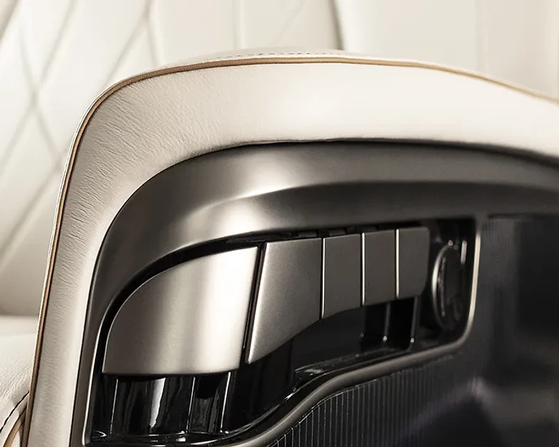 Close-up of a cream leather jet seat armrest with amber piping and a control console