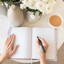 Hands writing in an open journal