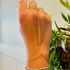 Gold permanent hand chain connecting a ring finger to stacked gold and silver bracelets by Oh She Linked
