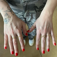 Gold permanent bracelets with dark bead charms and stacked gold rings by Oh She Linked