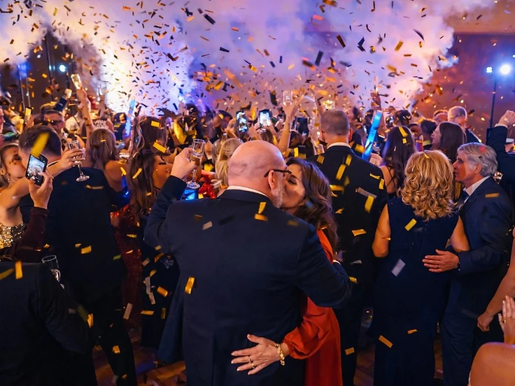 Couple kissing surrounded by gold confetti and a white CO2 fog plume on the dance floor