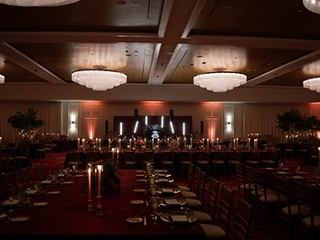 Grand ballroom at Turning Stone Resort Casino set for a wedding reception with crystal chandeliers and amber uplighting
