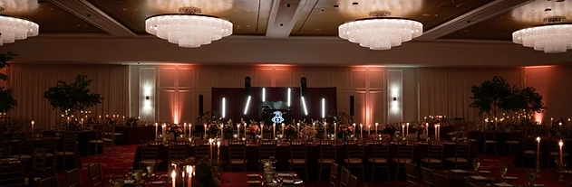 Grand ballroom at Turning Stone Resort Casino set for a wedding reception with crystal chandeliers and amber uplighting