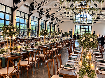 Long banquet tables with gold centerpiece stands and forest green runners set for a wedding reception inside The Lookout at Hope Lake