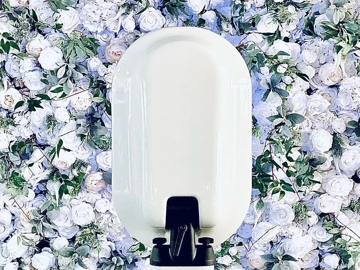 Photo booth kiosk in front of a lush white and pale blue flower wall