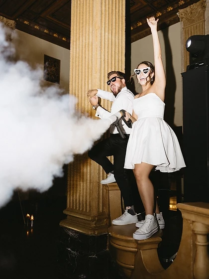 Couple firing a CO₂ smoke cannon together in a high-energy moment at their wedding reception