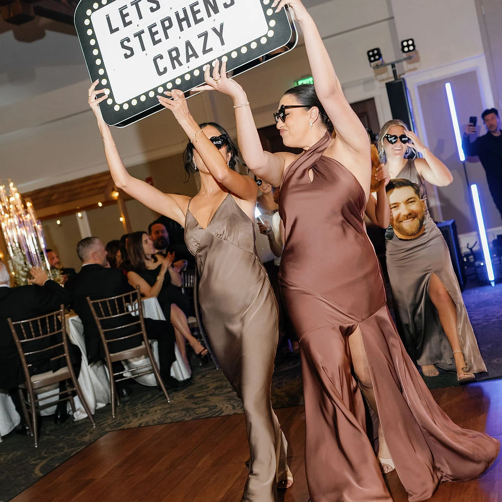 Guests carrying a marquee sign onto the dance floor at a luxury reception