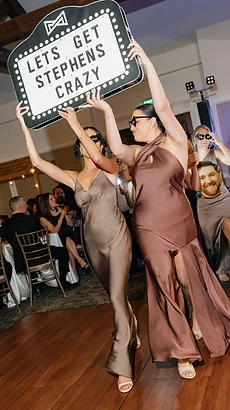Guests carrying a marquee sign onto the dance floor at a luxury reception