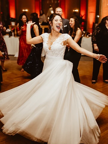 Kristin spinning with joyful laughter as guests clap on the dance floor