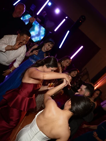 Bride dancing with her groom, viewed from behind, on a packed Turning Stone dance floor in the Oneida Room with vertical LED light tubes