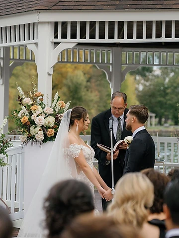 Bride and groom holding hands at the altar during Alexa and Dawson's wedding ceremony at Timber Banks Country Club