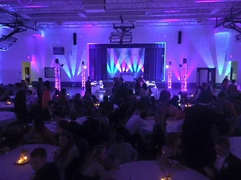 Stage wash lighting and LED truss towers filling a large event hall with color during a private celebration