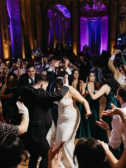 Wedding couple dancing energetically surrounded by guests on a lit dance floor