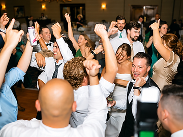 Guests dancing with arms raised on a packed dance floor at a Shenandoah Clubhouse wedding at Turning Stone