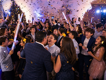 CO2 fog plume and gold confetti raining over a packed dance floor during a private celebration