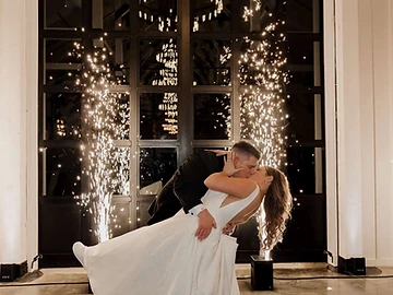 Bride and groom kissing between two cold spark fountains on the polished floor of The Lookout at Greek Peak Mountain Resort