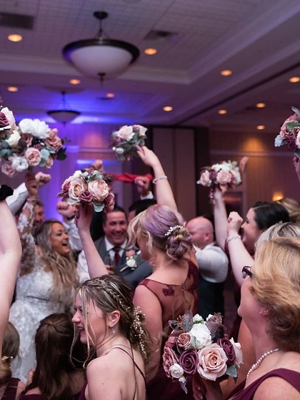 Bridesmaids holding their bouquets high on the dance floor at a wedding reception