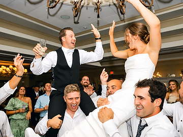 Bride and groom hoisted into the air by cheering guests on a packed dance floor at their Shenandoah Clubhouse wedding at Turning Stone