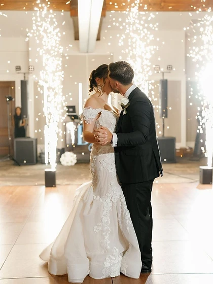 Couple dancing and kissing framed by two cold spark fountain machines at a wedding reception