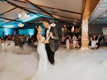 Bride and groom's first dance surrounded by dancing-on-the-clouds fog beneath the vaulted wooden beams of the Castle Ballroom at Belhurst Castle