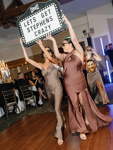 Bridesmaid holding a Let's Get Stephens Crazy marquee sign during the Bottle Service style introduction at Timber Banks Country Club
