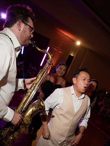 Saxophonist performing live during a Turning Stone wedding reception in the Oneida Room, with purple uplighting behind him