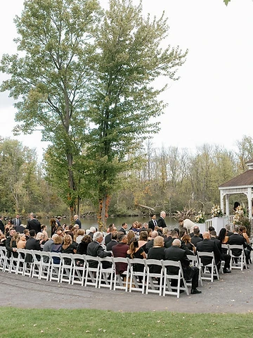 Guests seated in white chairs facing a white gazebo during Alexa and Dawson's outdoor wedding ceremony at Timber Banks Country Club