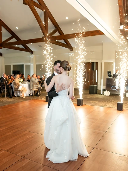 Bride and groom's first dance framed by two sparkler fountains in a rustic barn venue