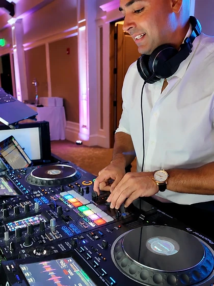 DJ Mike Melice smiling while mixing on a Pioneer controller at a wedding reception
