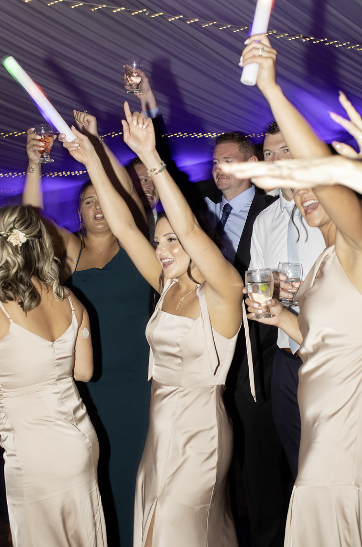 Wedding guests dancing with LED foam batons under purple uplighting at John Joseph Inn in Groton, near Ithaca