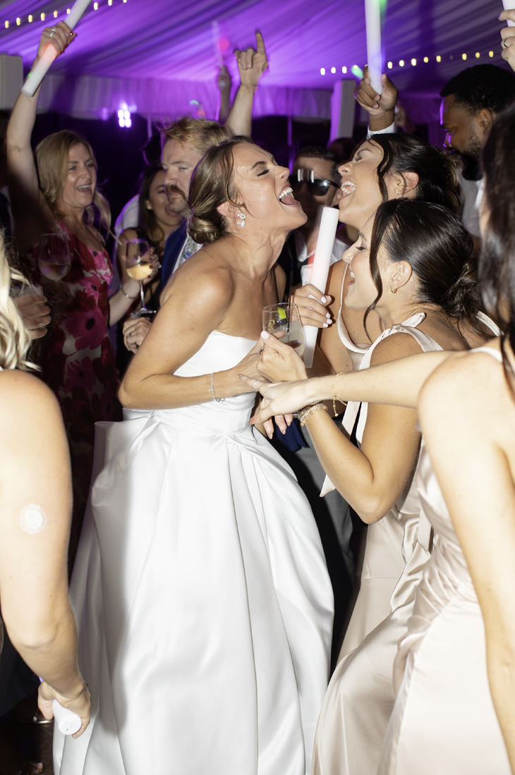 Bride dancing with LED foam sticks during a packed dance floor moment at John Joseph Inn in Groton, near Ithaca