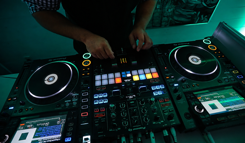 DJ hands on a Pioneer DJ mixing console bathed in teal light