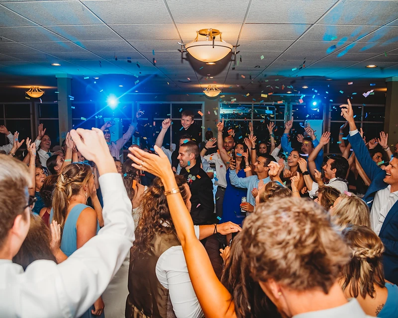 Crowd celebrating on a dance floor under blue stage lighting at a corporate event