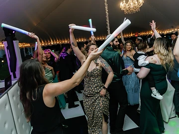 Guests dancing with glowing LED foam light batons on a packed dance floor at a Geneva On The Lake wedding reception