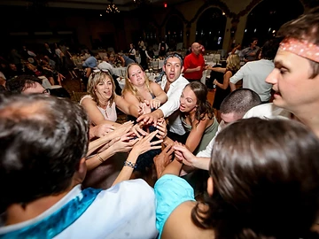 Wedding guests gathered in a circle with their hands stacked in the center of the dance floor at a Ventosa Vineyards wedding reception
