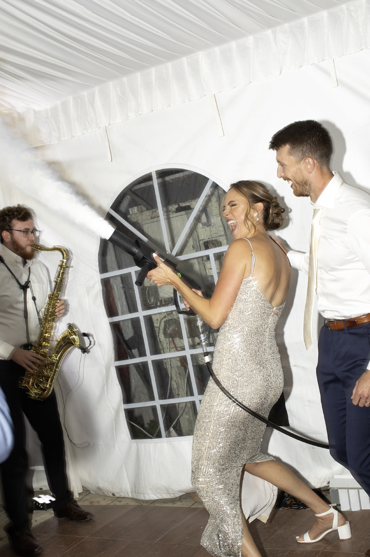 Bride holding a CO2 cannon during a high-energy moment on the dance floor at John Joseph Inn in Groton, near Ithaca