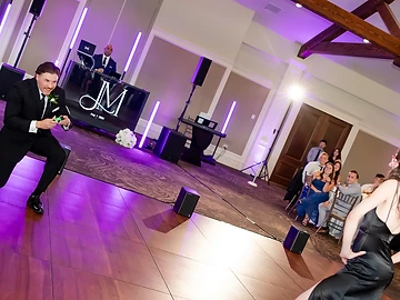 Monogrammed DJ booth with vertical LED light tubes and purple uplighting at a wedding reception set for the wedding party introductions