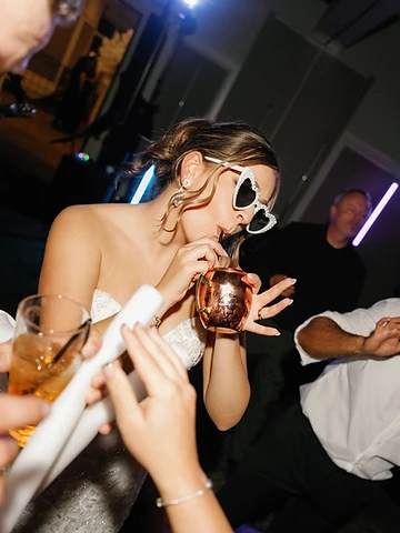Bride wearing heart-shaped sunglasses celebrating on the dance floor at Timber Banks Country Club
