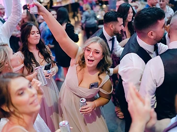 Guests celebrating on a packed dance floor beneath blue and purple lighting at a Greek Peak wedding reception