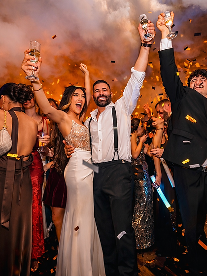 Bride and groom toasting with champagne amid falling gold confetti at their wedding