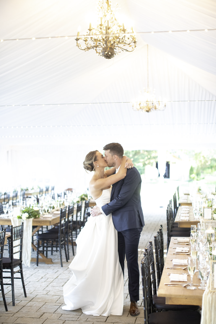Bride and groom kissing under the chandelier at their John Joseph Inn wedding reception in Groton, near Ithaca