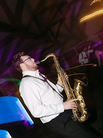 Saxophonist performing live with purple stage lighting during Maria and Joseph's wedding reception at Timber Banks Country Club