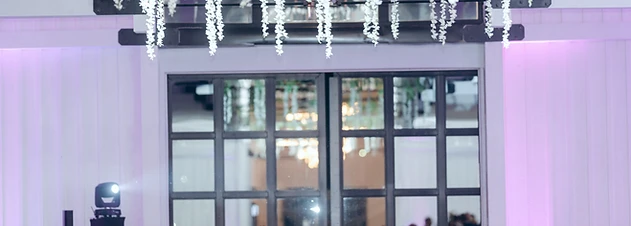 Wedding reception beneath the vaulted white rafters and circular Edison-bulb chandeliers of The Lookout at Hope Lake at Greek Peak Mountain Resort