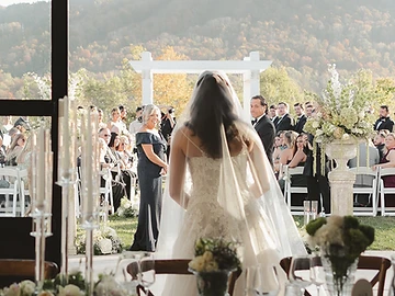 Bride framed in the black steel doorway of The Lookout looking out toward an outdoor ceremony with white chairs and autumn mountain views
