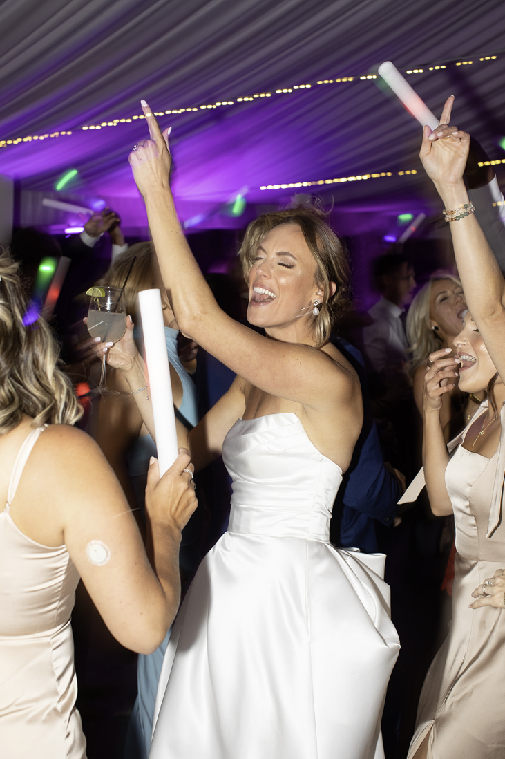 Bride celebrating on the dance floor with LED light sticks at John Joseph Inn in Groton, near Ithaca
