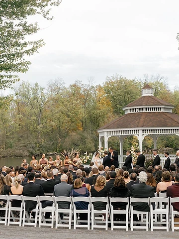 Bride and groom exchanging vows in a white gazebo with their wedding party during Alexa and Dawson's ceremony at Timber Banks Country Club