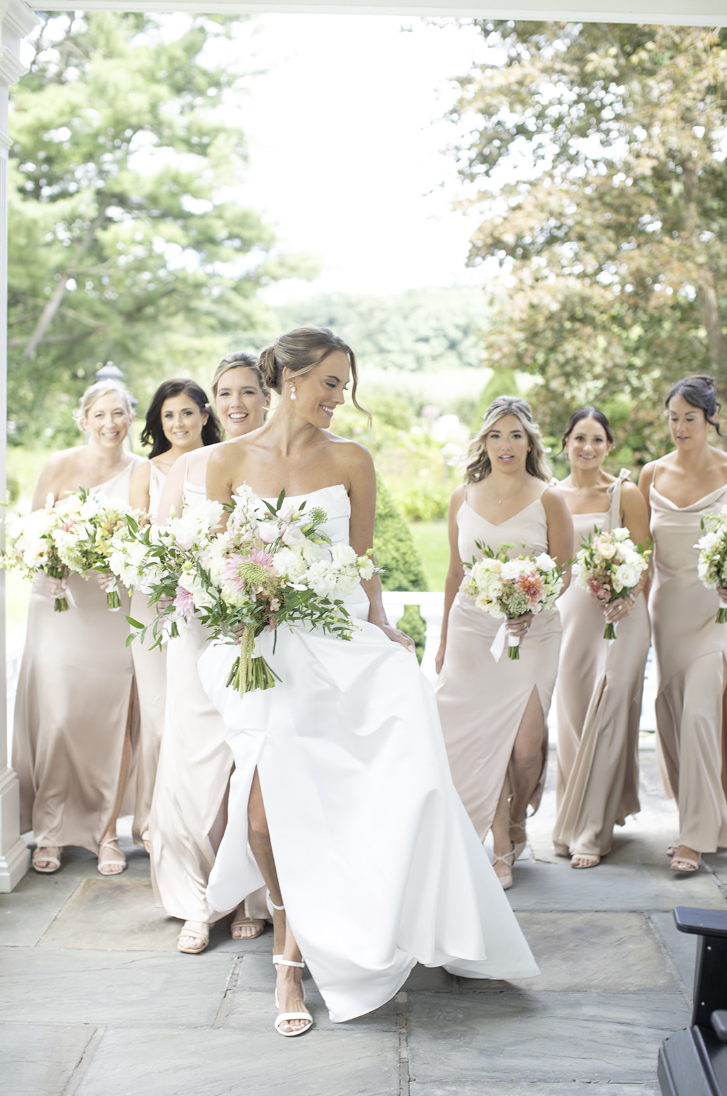 Bride walking with her bridesmaids on the stone patio at John Joseph Inn in Groton, near Ithaca