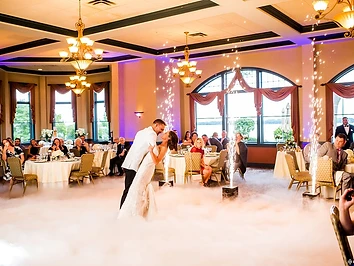 Bride and groom in a dance dip framed by four cold spark fountains and dancing-on-the-clouds fog in the Meritage Ballroom at Belhurst Castle