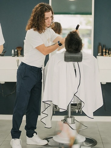 Barbeiro a pentear e finalizar corte de cabelo