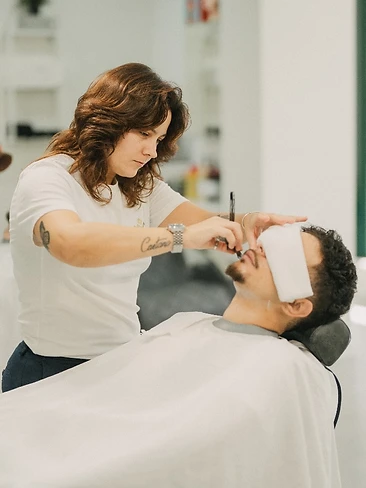 Cliente satisfeito a sorrir após corte finalizado pelo barbeiro